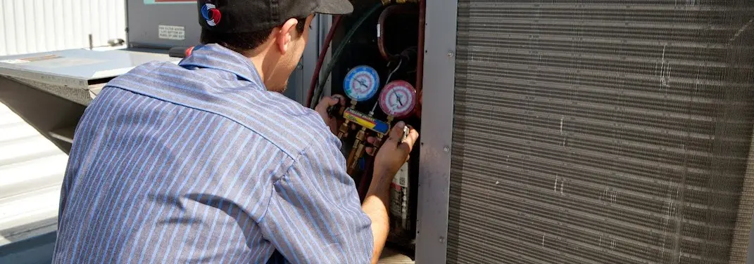 HVAC technician servicing a condenser unit in Centerville